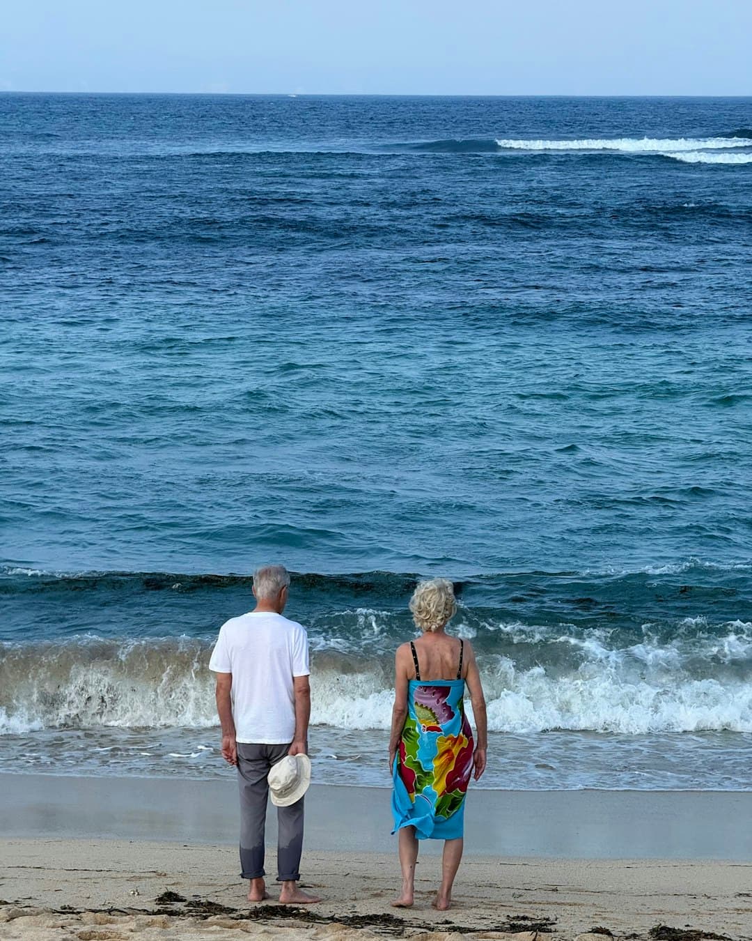 An older couple standing together at the water’s edge
